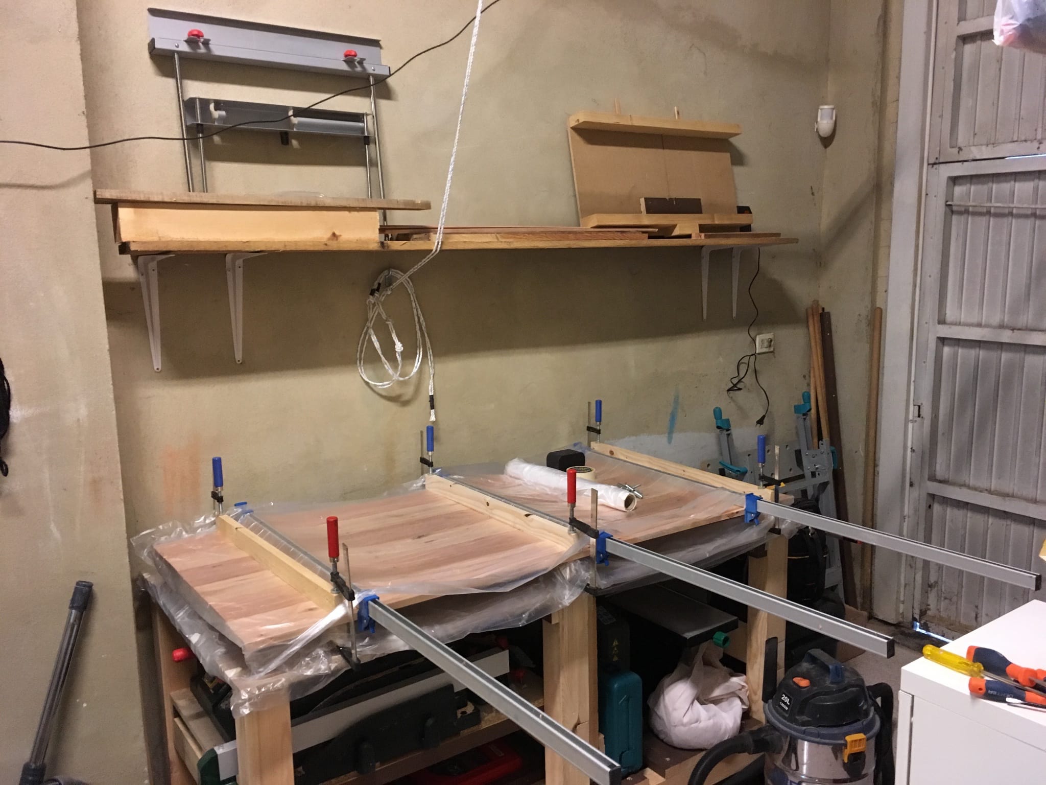 A wooden tabletop held together with clamps during the gluing process {caption: The table top being glued together}