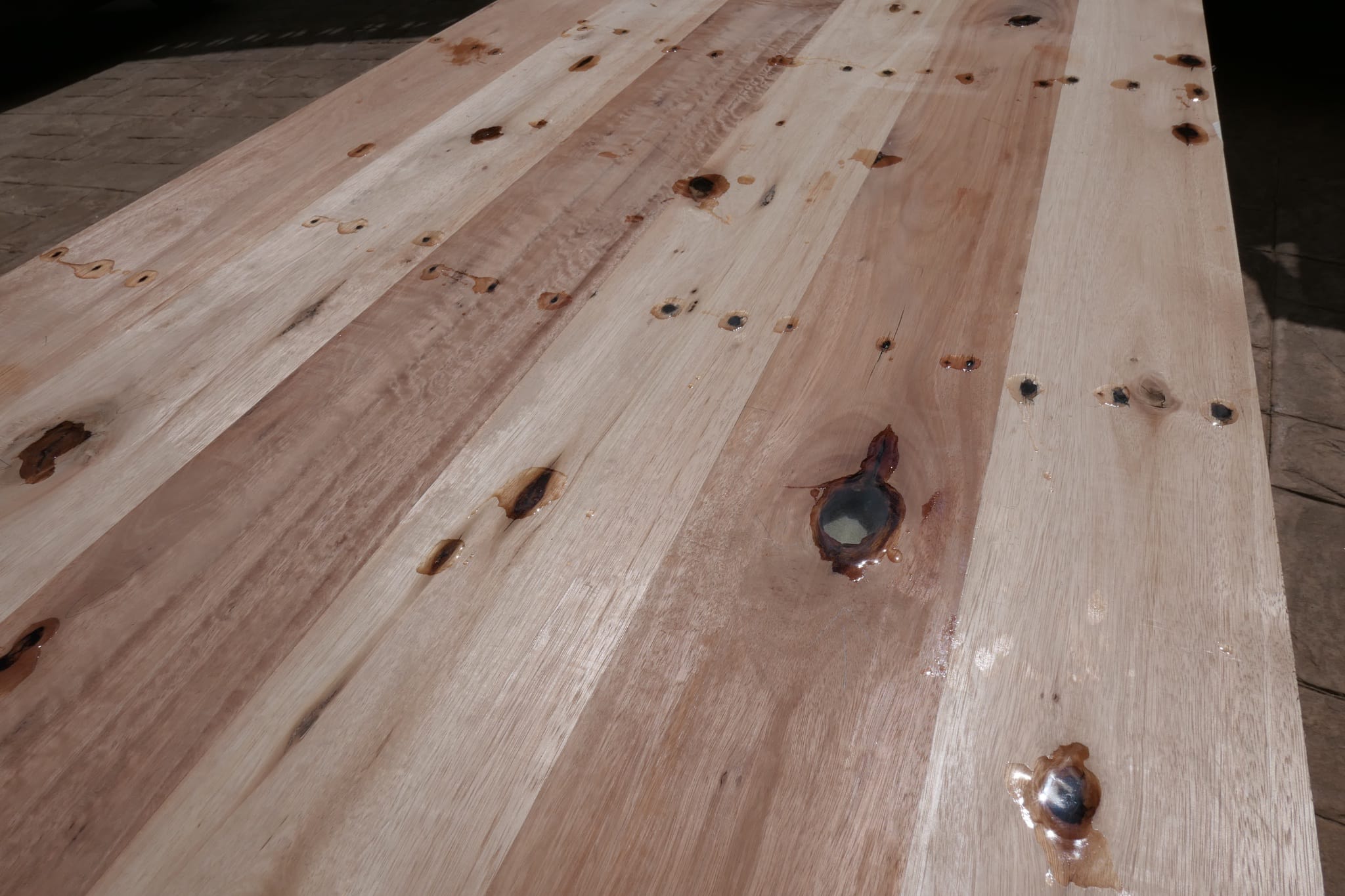 Clear resin poured into the knot holes of a wooden tabletop {caption: Filling the knot holes with clear resin}